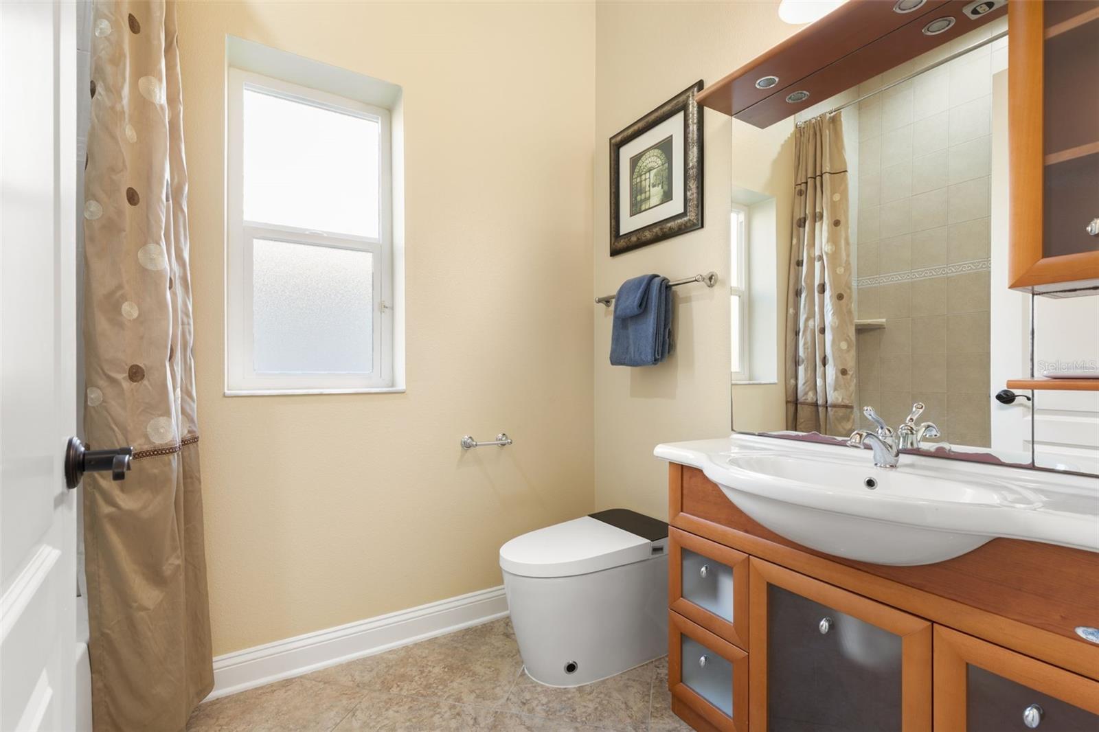 Italian-inspired first-floor guest bathroom featuring distinctive wood cabinetry, decorative tile flooring, and a tub/shower combination.