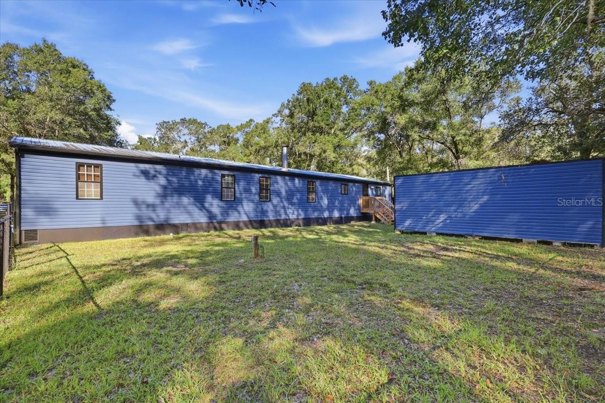 Back of home showing back stairs and Shed.