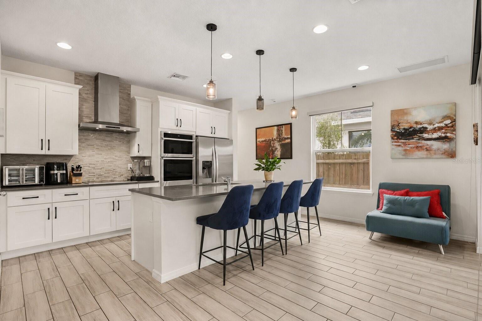 Modern kitchen featuring a large center island with seating, built-in appliances, solid surface countertops, and abundant cabinetry. Modern kitchen featuring a large center island with seating, built-in appliances, solid surface countertops, and abundant cabinetry.