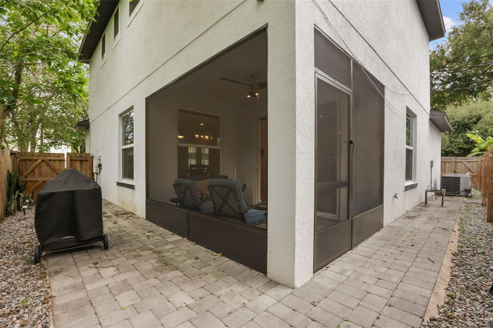 Exterior view showcasing the screened lanai, paver patio, and low-maintenance outdoor living space.
