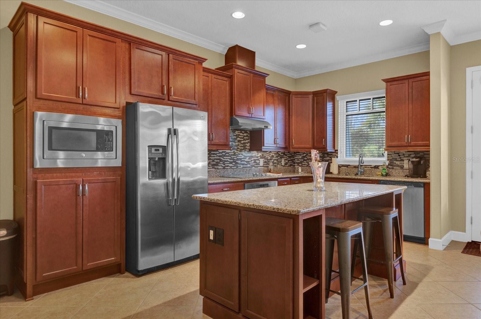 Rich cherry cabinetry paired with stainless steel appliances creates a warm, functional chef's kitchen.