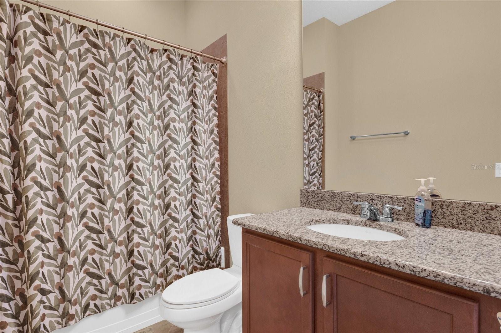 Full guest bathroom with tub/shower combo and vanity storage.