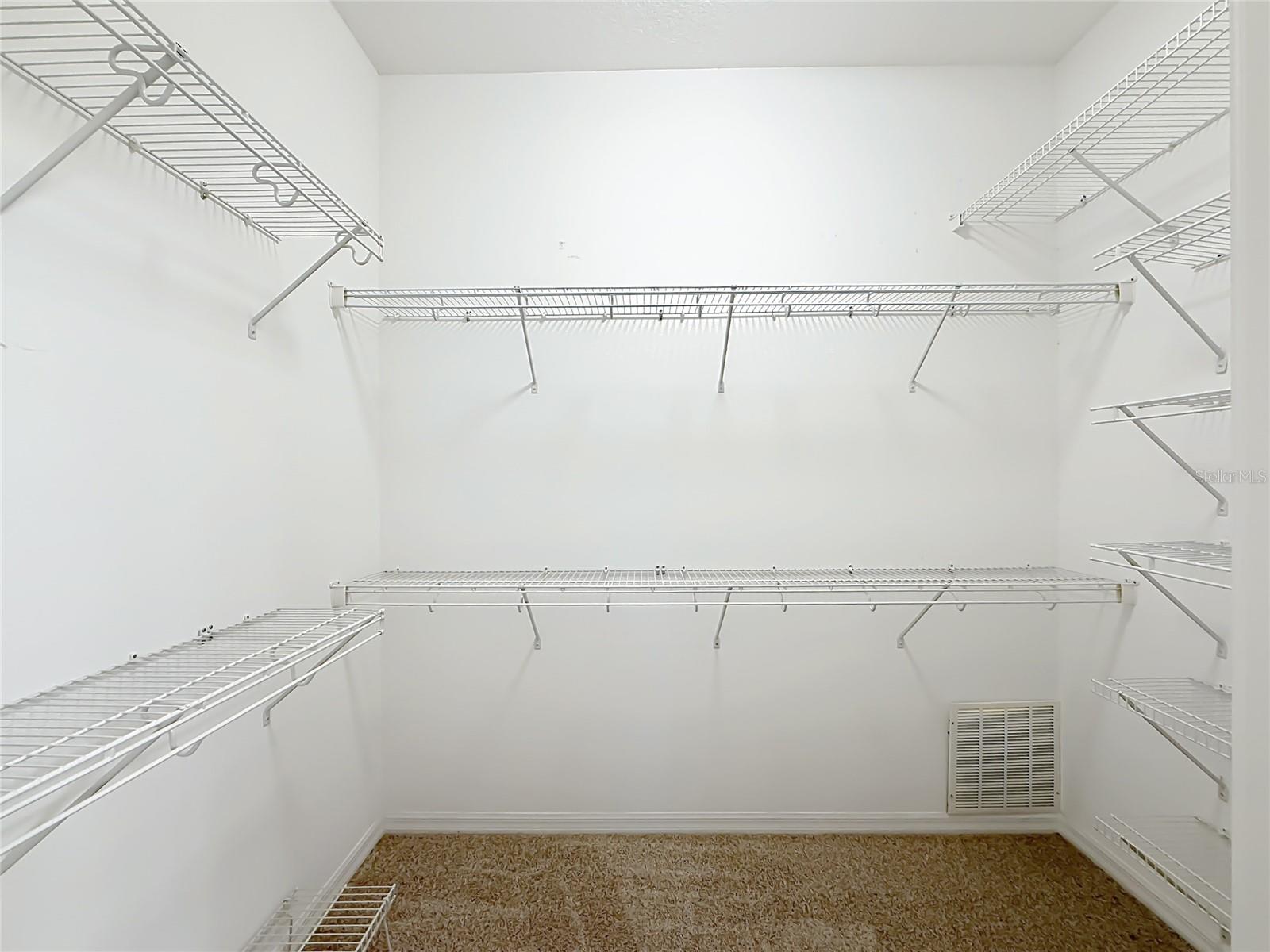 Large Walk in closet with racks and new carpet.