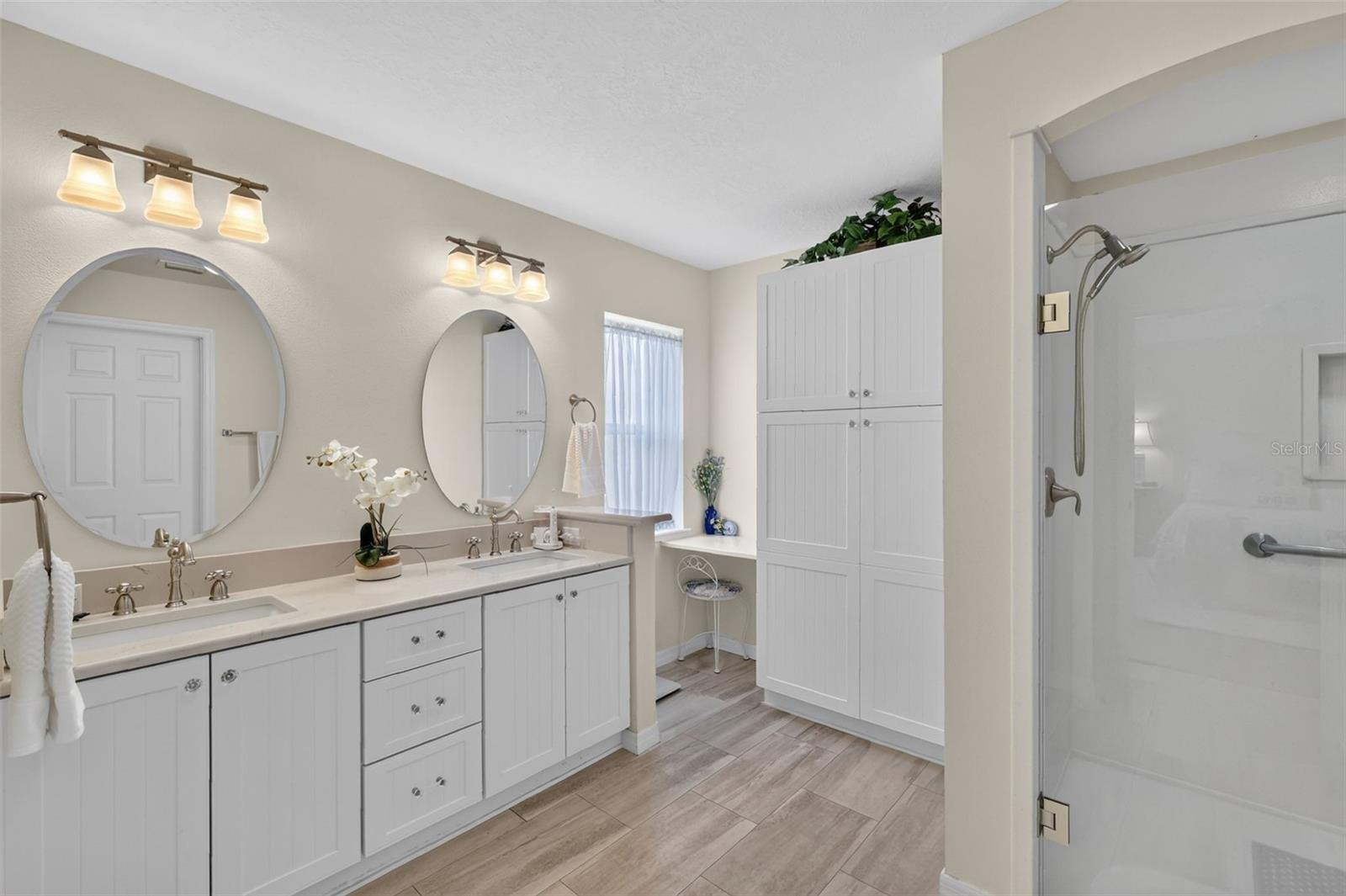 Double sink vanity with linen closet and walk in shower