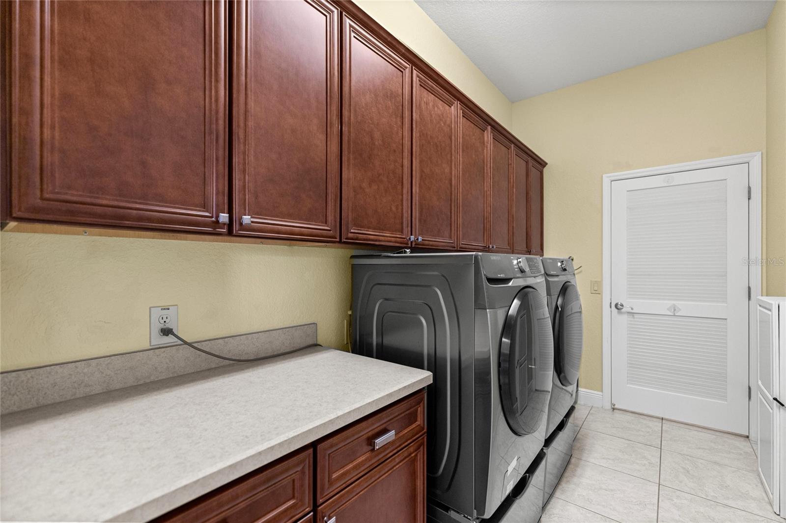 Indoor Laundry Room with Custom Cabinetry, Utility Sink, and Folding Counter.
