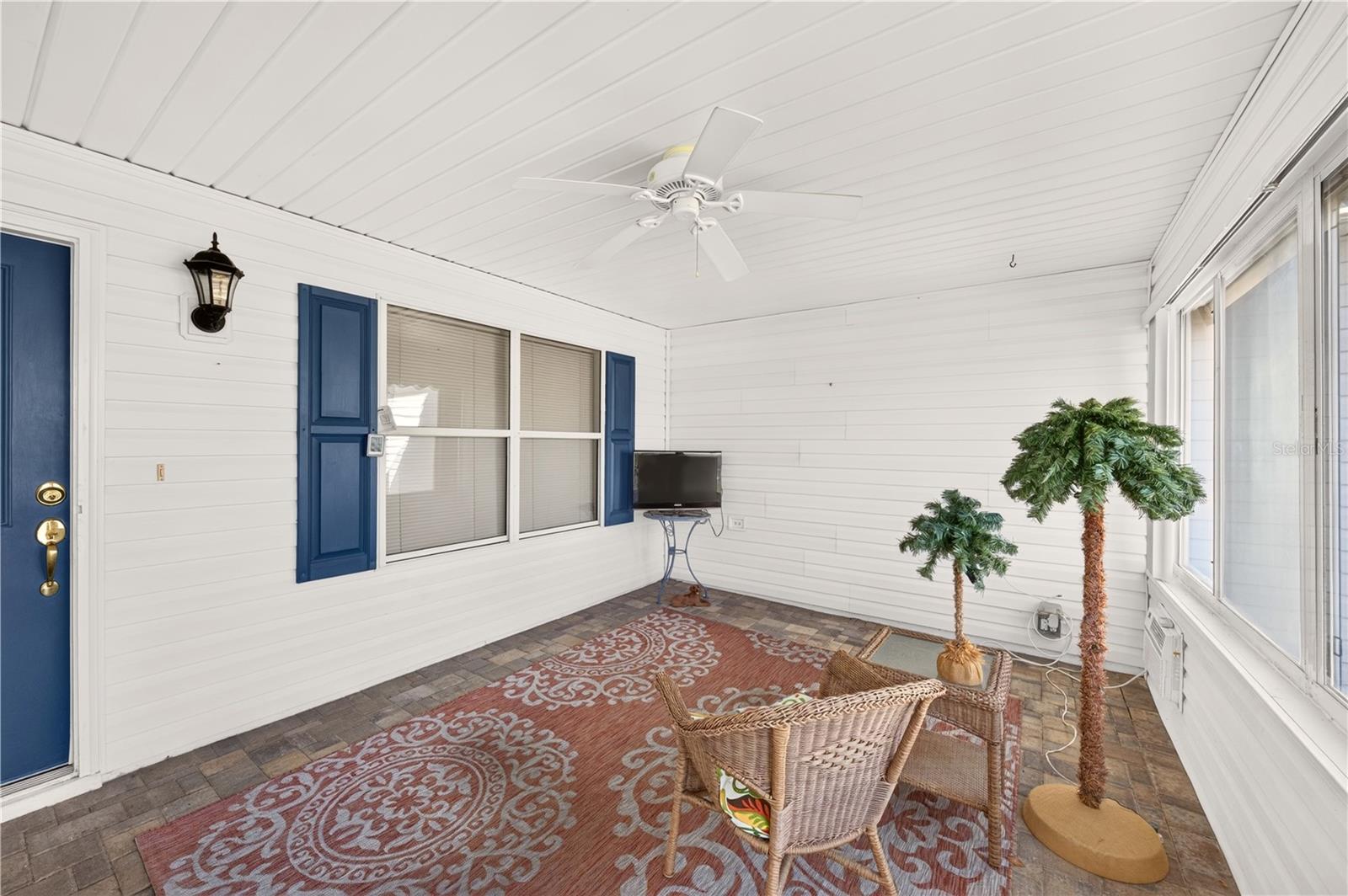 Charming enclosed front porch featuring brick-paver flooring, a ceiling fan, abundant windows, and comfortable seating space. An inviting area to relax and enjoy the Florida lifestyle. Charming enclosed front porch featuring brick-paver flooring, a ceiling fan, abundant windows, and comfortable seating space. An inviting area to relax and enjoy the Florida lifestyle.