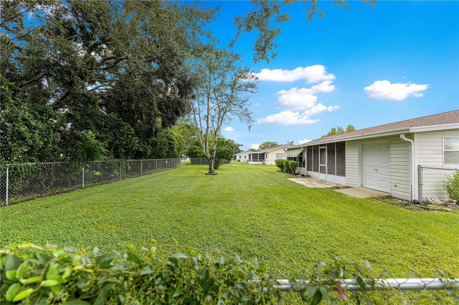 FENCED IN BACKYARD SHOWING BACK OF THE HOUSE AND GOLF-CART GARAGE
