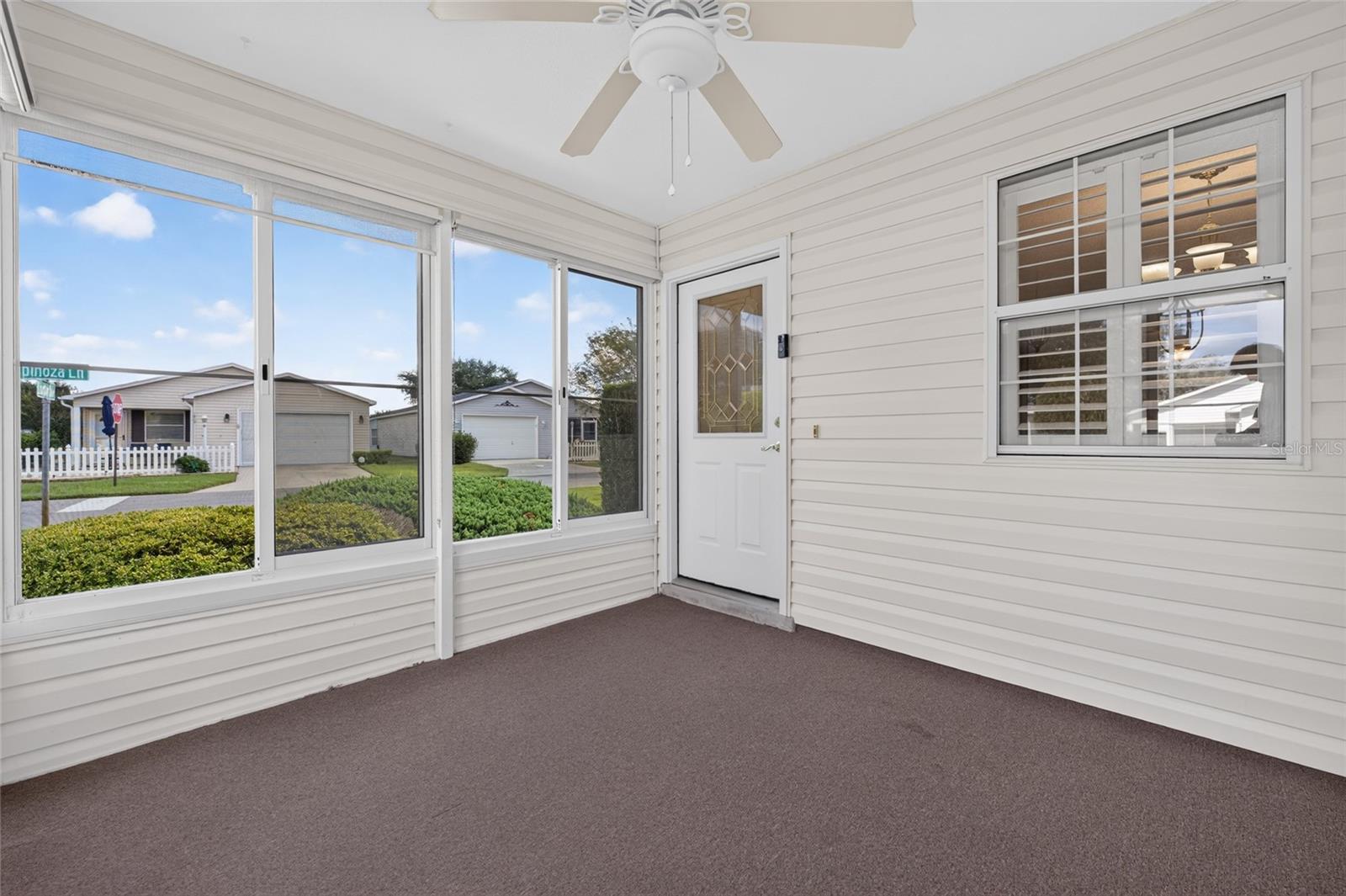 ENCLOSED LANAI / FRONT ENTRY - A half-lite front door with a DECORATIVE LEADED-GLASS INSERT design of geometric shpes, privacy glass & bright brass caming welcomes you into this lovely villa.