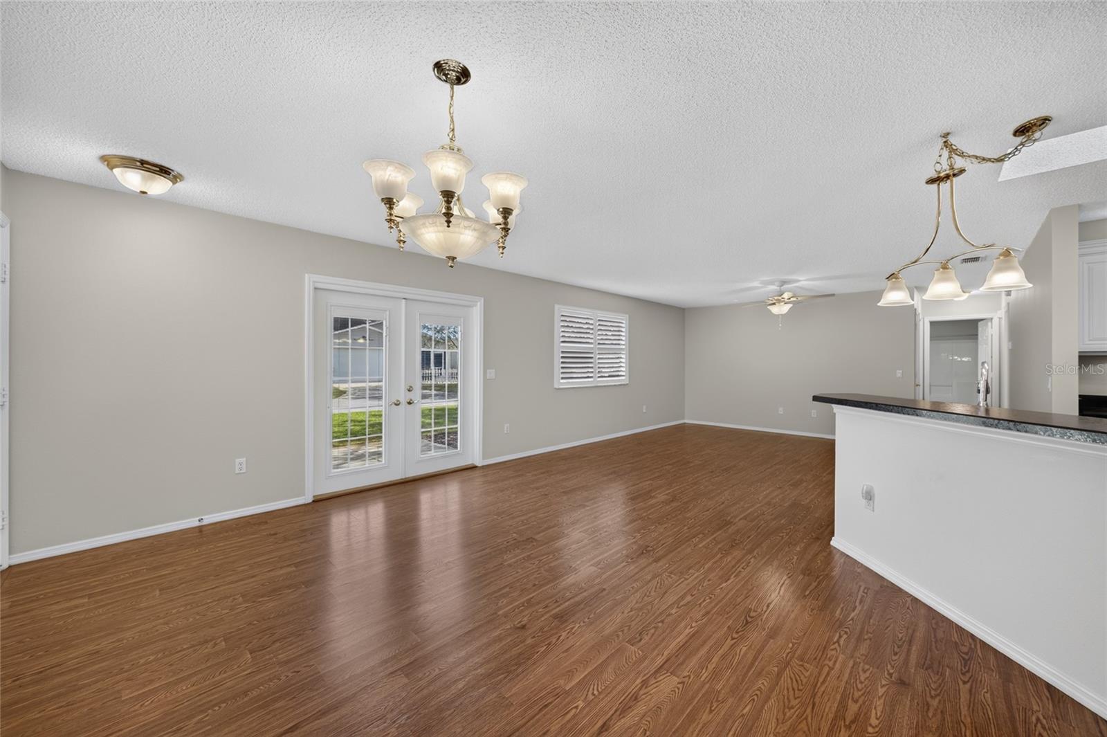 Overview of DINING / KITCHEN/LIVING ROOM - A dining chandelier, breakfast-bar pendant and a new ceiling fan w/ alabaster-white bowl coordinate the lighting across the connected spaces.