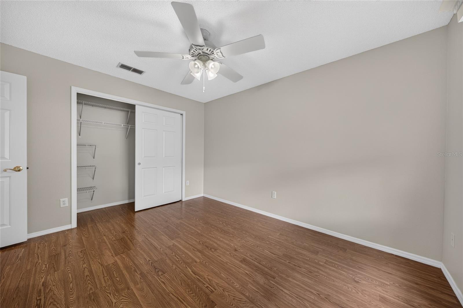 BEDROOM #2 - Open closet view reveals shelving and hanging space behind the double closet doors.