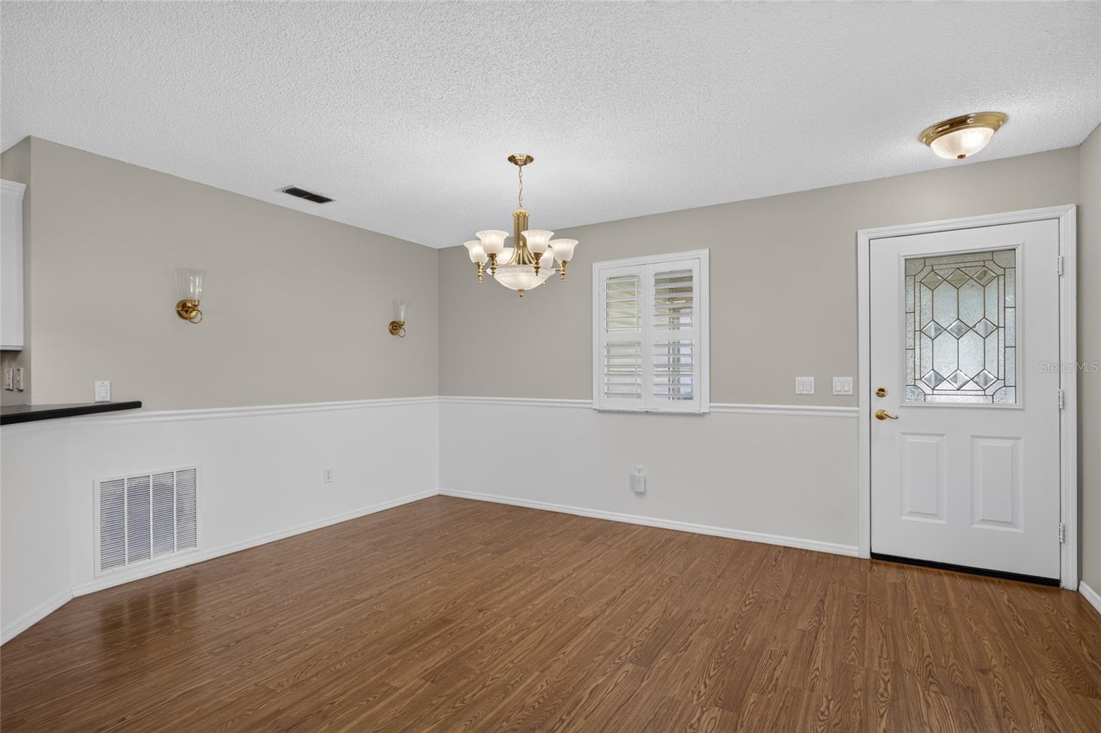 Close up view of DINING AREA - Alternate angle showing the chair rail and back of FRONT DOOR w/ half-lite decorative glass insert.