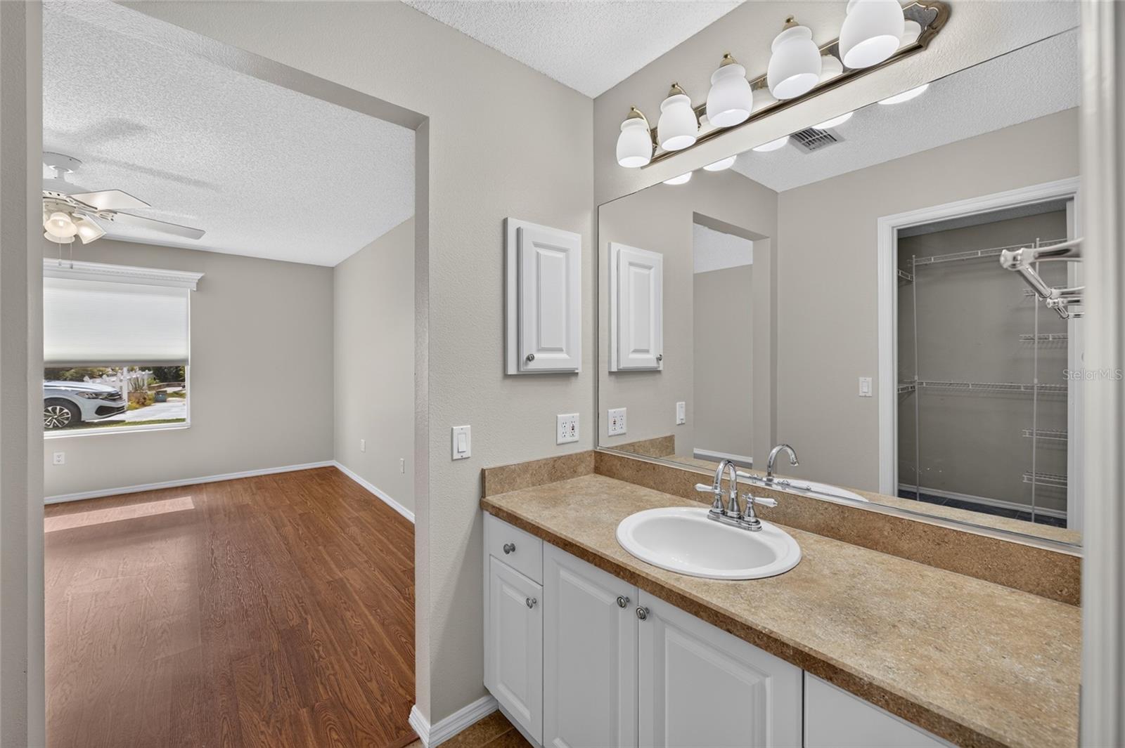ENSUITE PRIMARY BATHROOM Vanity area - View from the single-sink vanity into the adjoining PRIMARY BEDROOM.