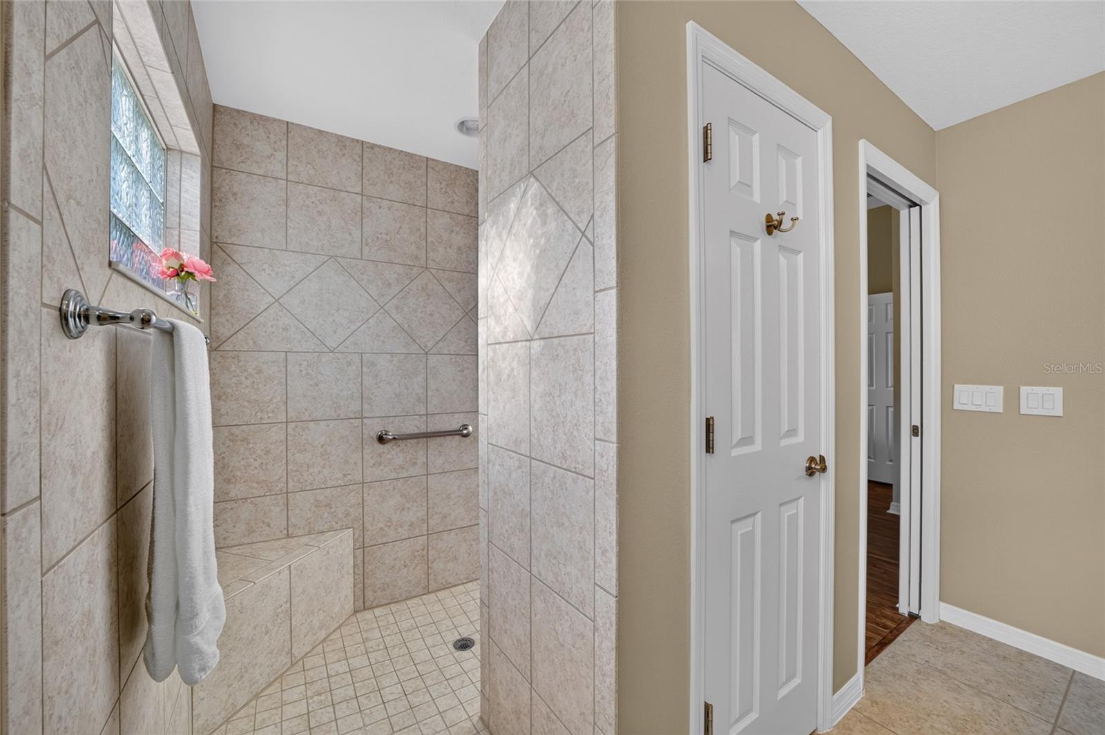 Walk-in tiled roman shower with corner bench seat