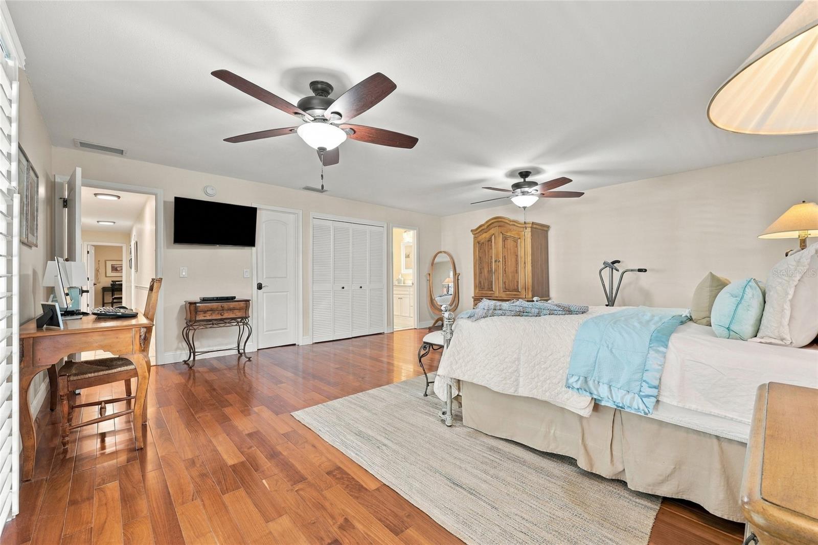 Primary bedroom with teak engineered floors & plantation shutters