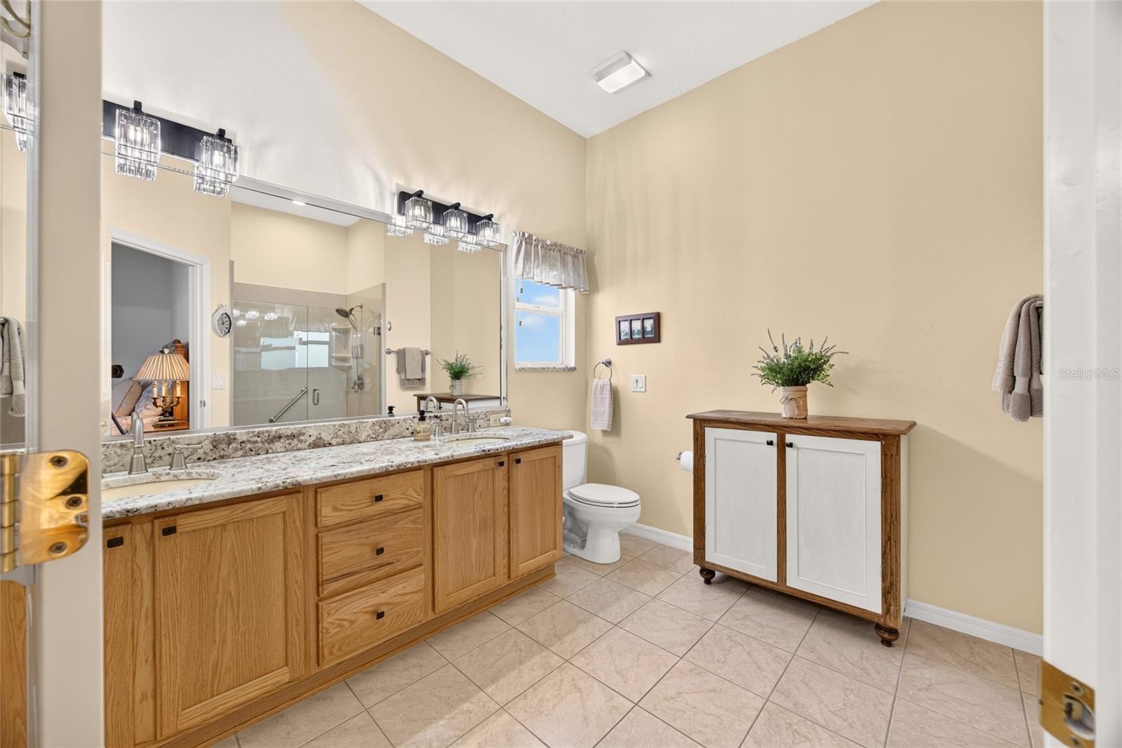 The primary bath features a spacious vanity with dual sinks, ample cabinet storage, and a large mirror with overhead lighting.