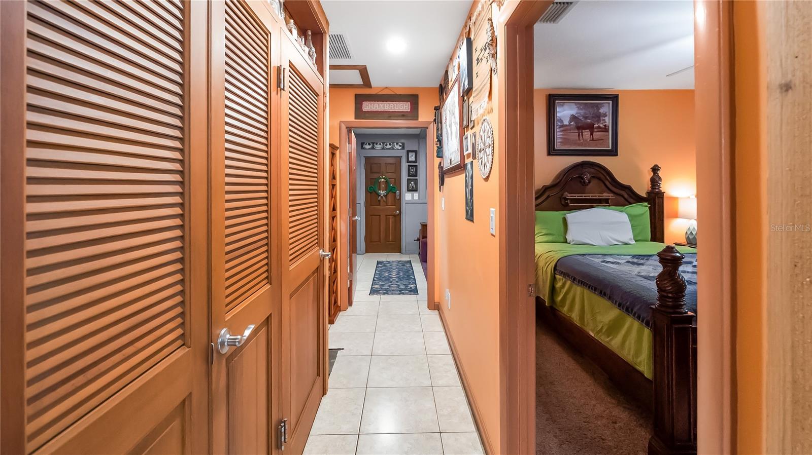 Hall way on guest north side of the main home. Two bedrooms (one being used as TV room, Full bathroom and laundry room. wall of storage closets that lead to an exit door to pool. Easiy access to guest bathroom from pool.