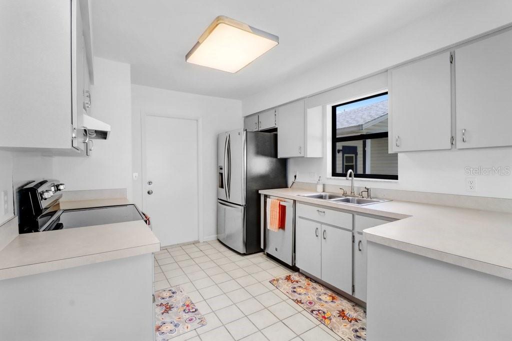 Kitchen ~ with new light fixture, new cabinet hinges and pulls,  and stainless steel appliances ~ opens to the dinette and the door provides access to the two car garage.