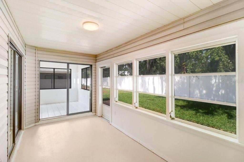 Enclosed porch surrounded by two sliding glass doors in front and to the left.  To the right a wall of windows and a screen door providing access to rear terrace and yard.