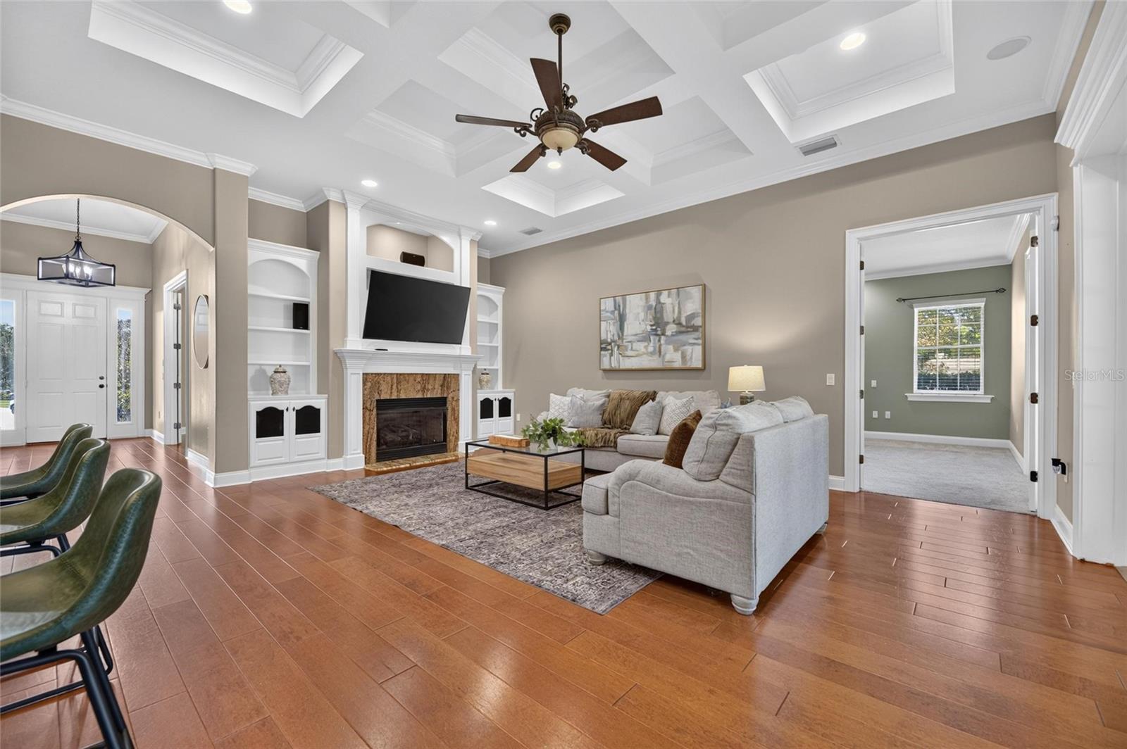 Stunning Living room with tray ceiling, gas fireplace, custom built in and beautiful hardwood flooring