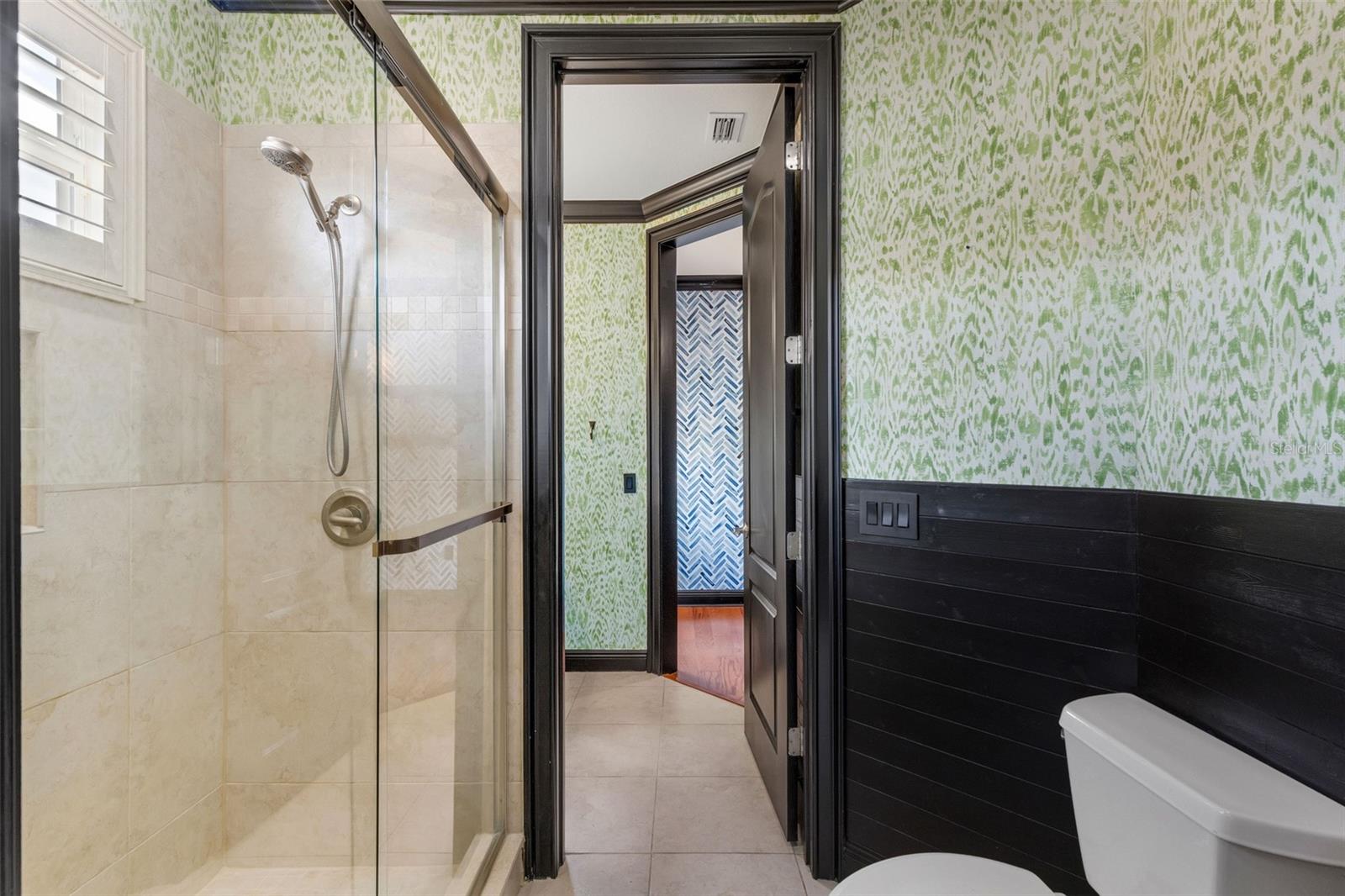 The shared part of this bathroom has a fully tiled shower with custom glass enclosure.