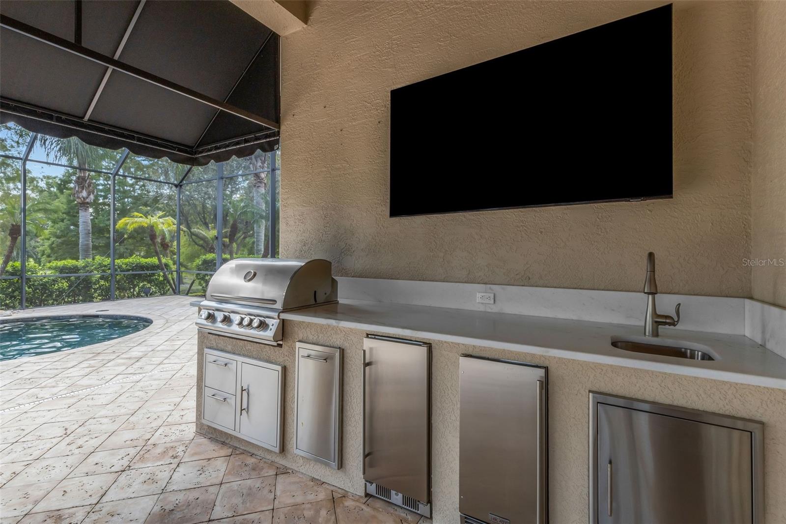 Where you will find a built-in summer kitchen with gas grill, refrigeration units, sink and more!
