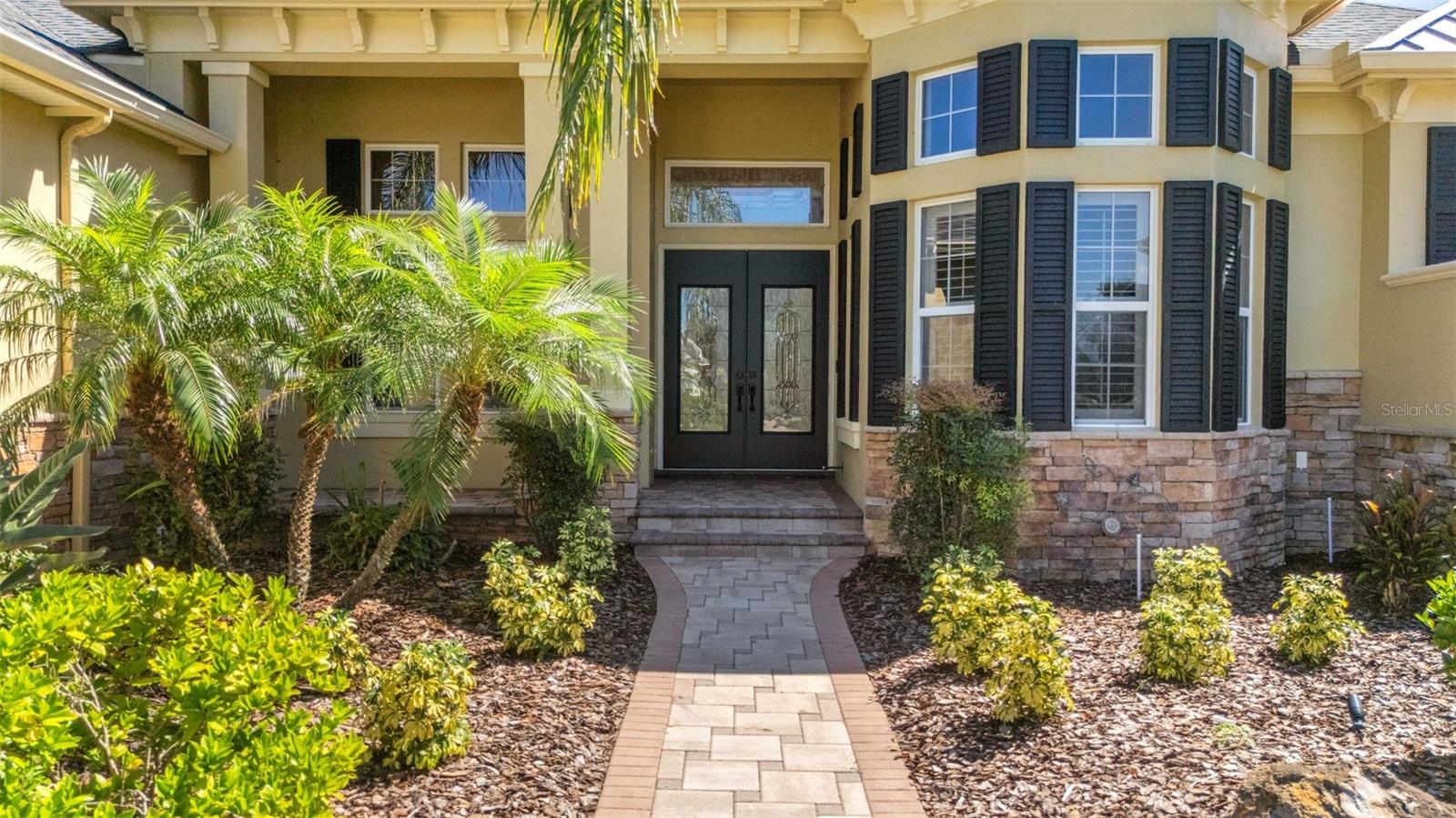 The wide deep elevated entry boasts stone accents, brick pavers and dual leaded glass entry doors. The wide deep elevated entry boasts stone accents, brick pavers and dual leaded glass entry doors.