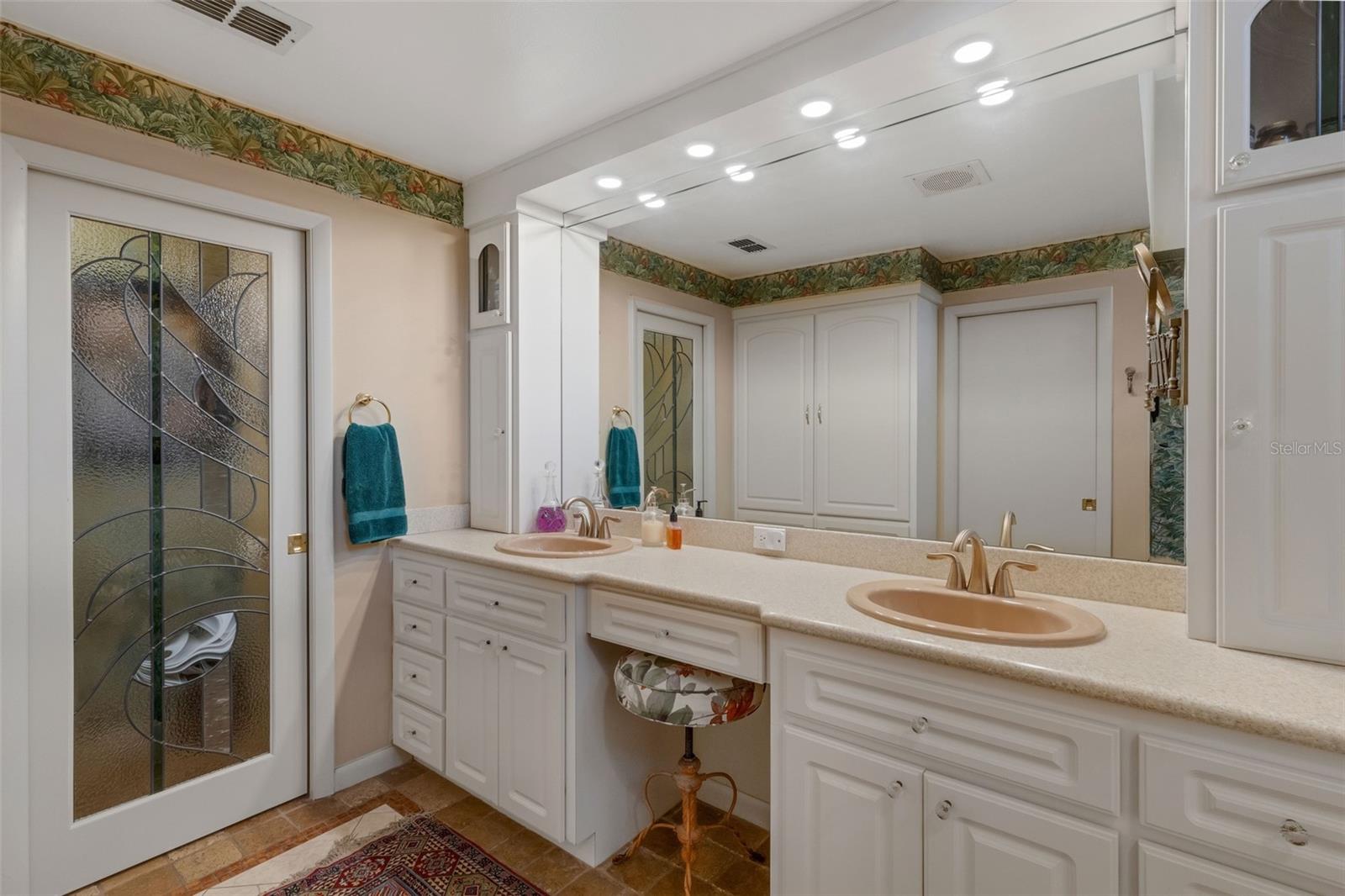 The ensuite bathroom features a long dual sink vanity with sitdown makeup area and tower storage at either end.