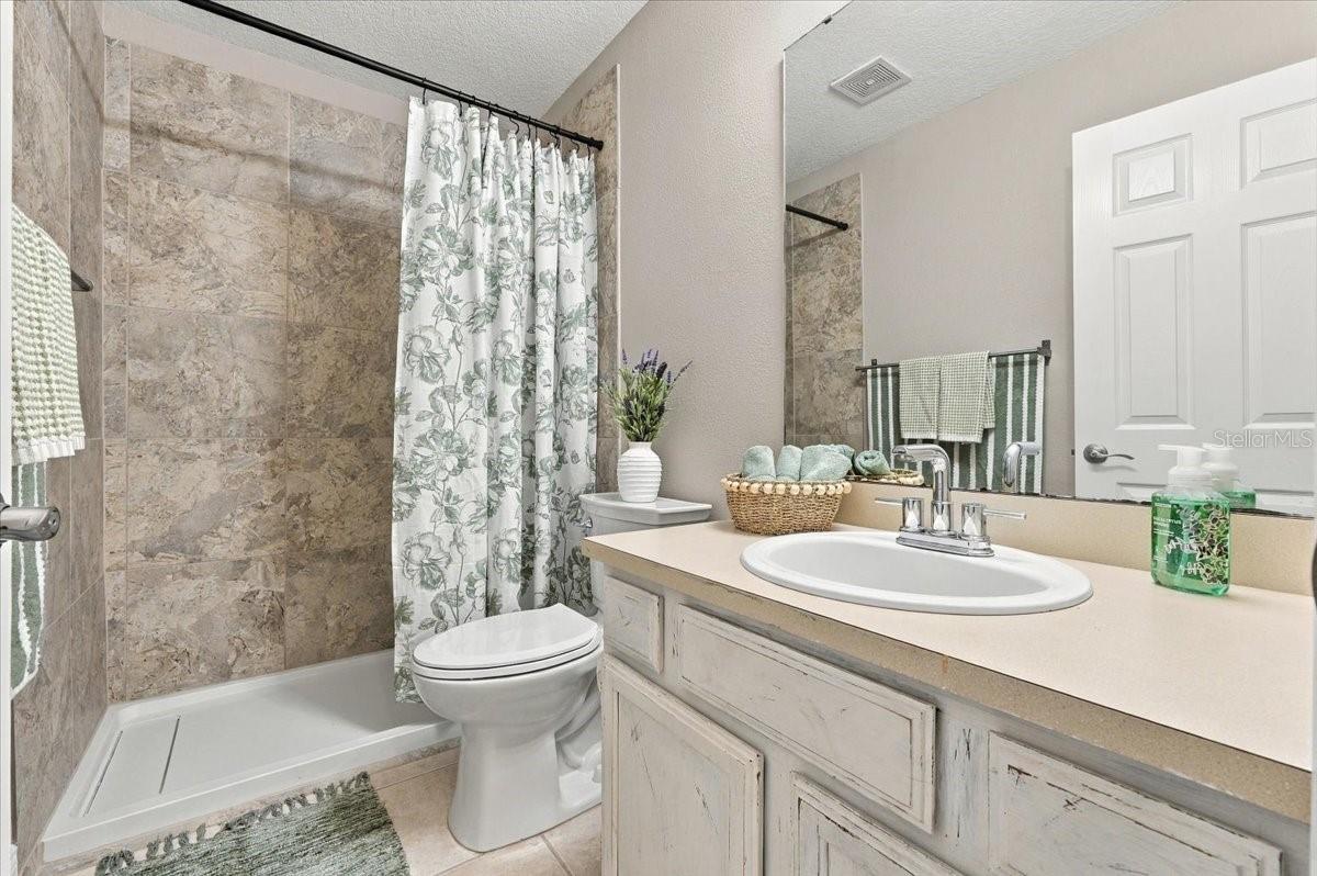 Guest bath with updated shower, new toilet ceramic tile flooring.