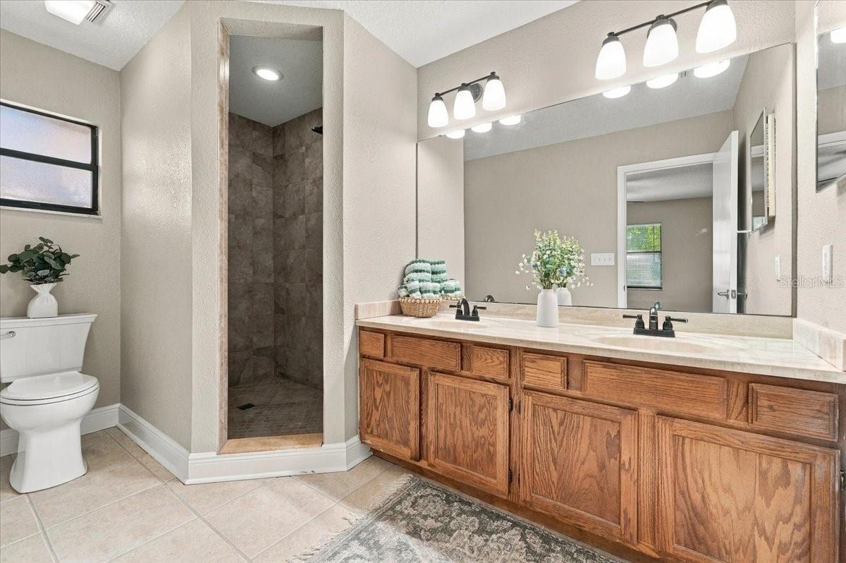 Primary Bath with Dual sinks, walk in shower, new toilet and cermic tile flooring.