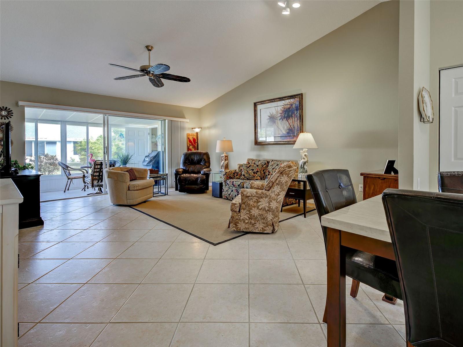 living room with high cathedral ceiling, tile flooring, sliding glass doors to lanai. Open floor plan