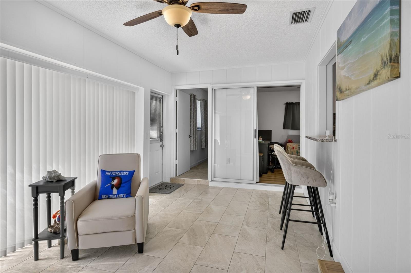 Family room with bar stools at a counter that looks through to kitchen