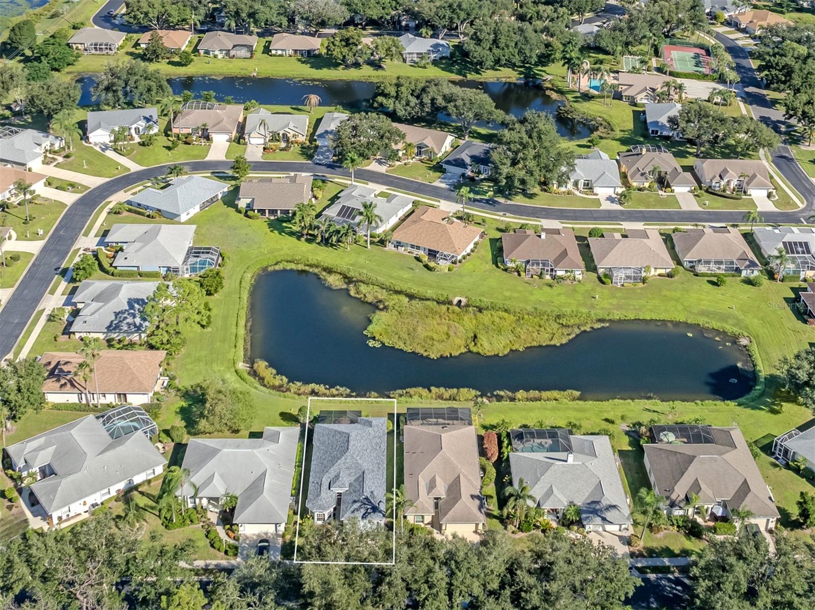 A view that truly speaks for itself! From high above, discover the wonderful harmony of sparkling blue water, lush tropical greenery, and a beautifully situated home where every day brings a little more sunshine, serenity, and Florida magic!