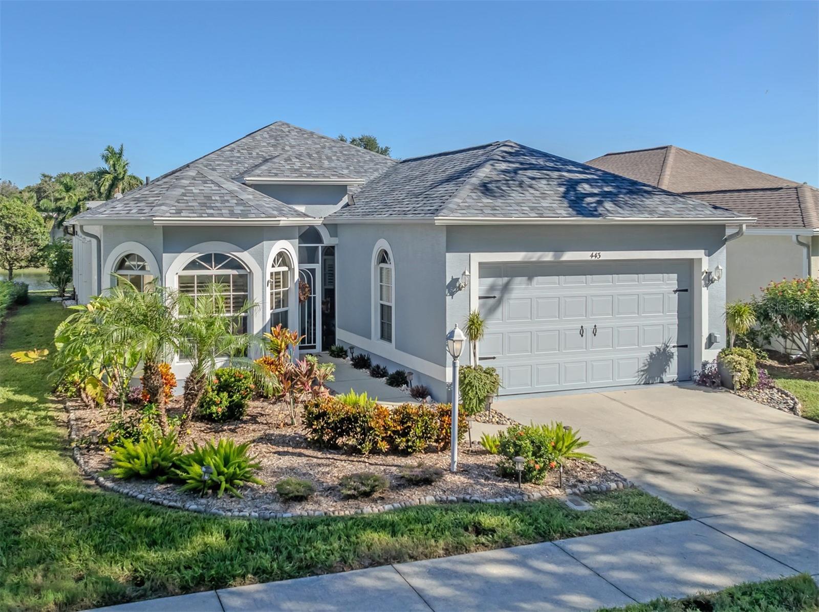 Beautiful curb appeal welcomes you home, featuring a charming bay window, lush mature landscaping, and a lovely glimpse of the peaceful lake beyond!