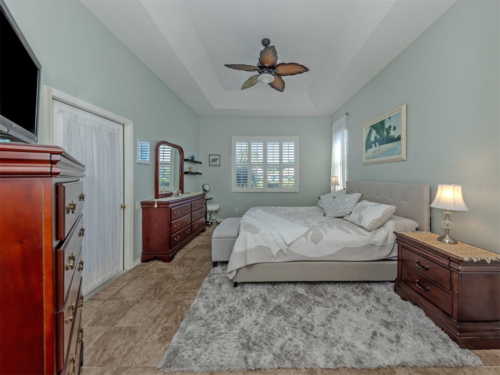 Your own private slice of paradise! This beautiful primary suite is a delightful retreat, featuring an elegant tray ceiling, ceiling fan, gorgeous ceramic tile flooring that flows seamlessly throughout the home, and lovely lake views! Step directly onto the extended lanai to enjoy the Florida sunshine, while two closets, including a generous walk-in, provide plenty of room for your wardrobe!