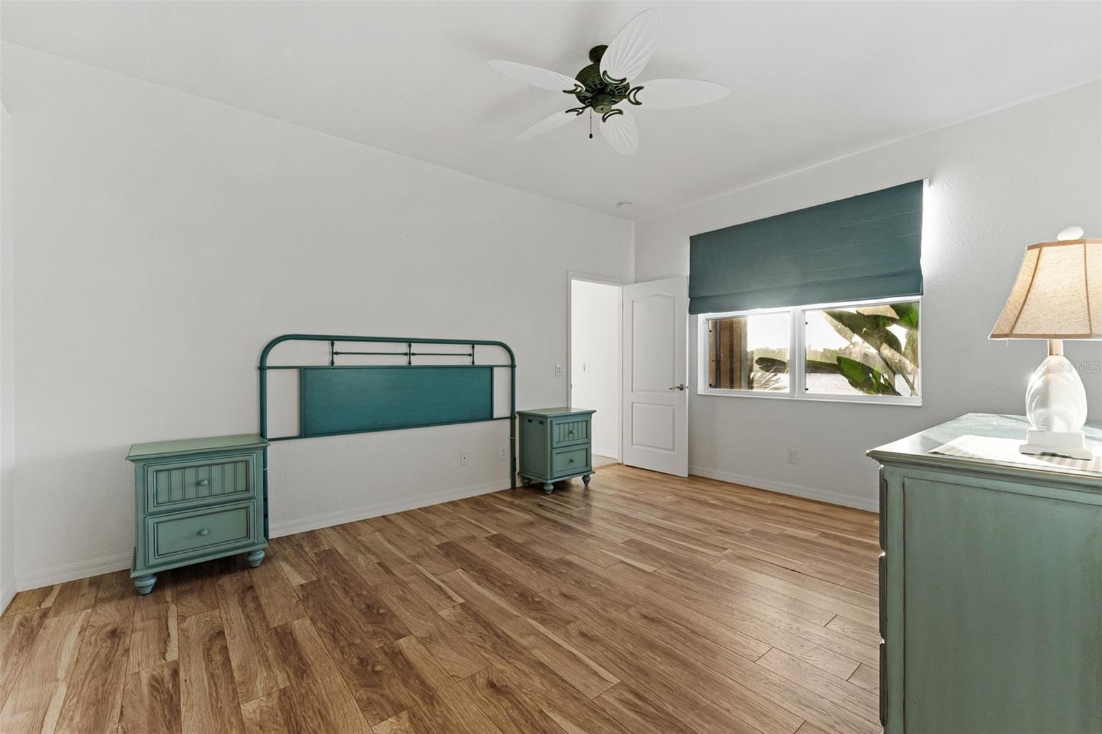 Another view of the spacious bedroom featuring warm wood flooring & plenty of room for additional or different furnishings