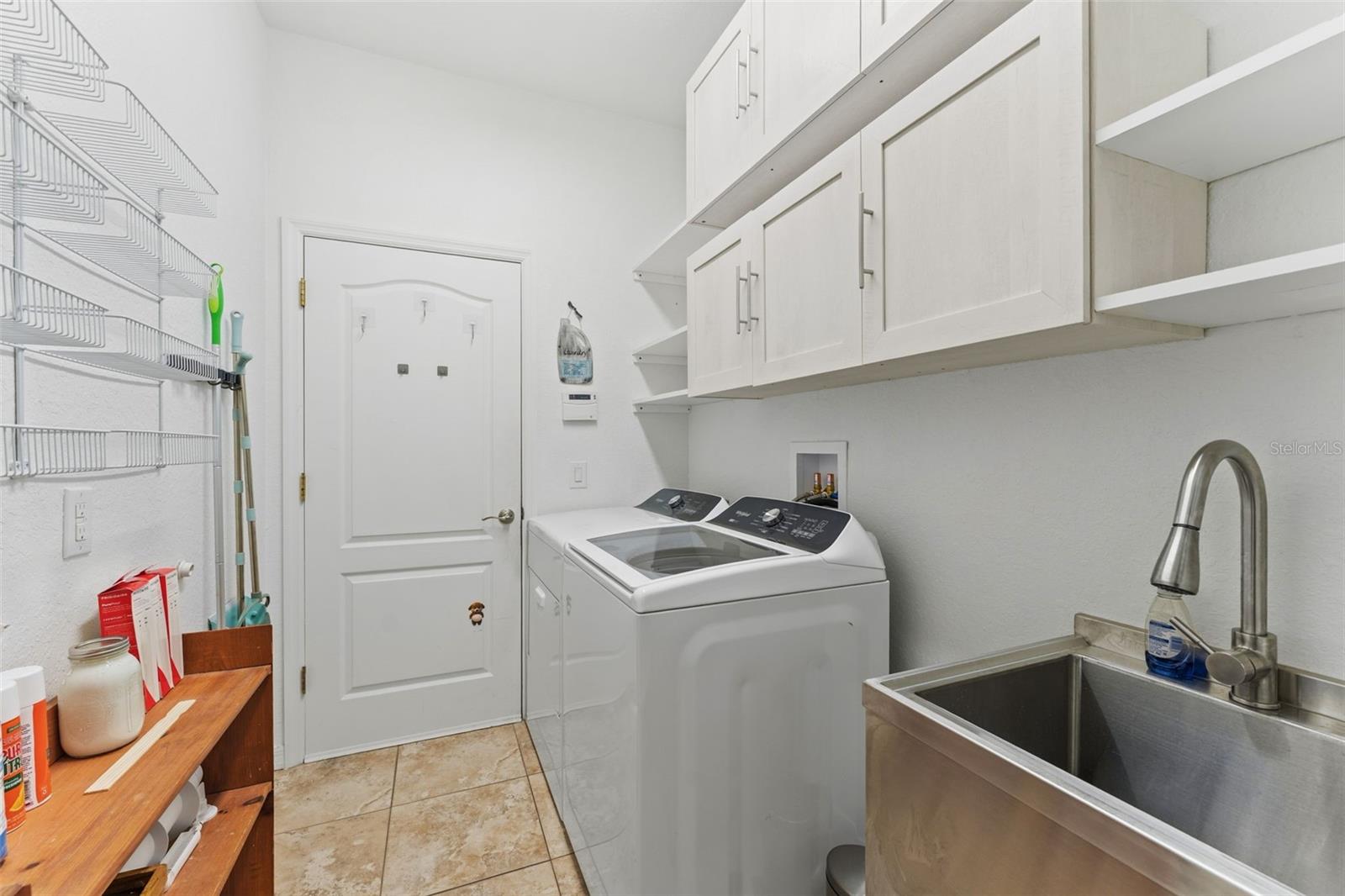 Laundry Room with full size washer/dryer and stainless steel utility sink as well as cupboard and shelf space