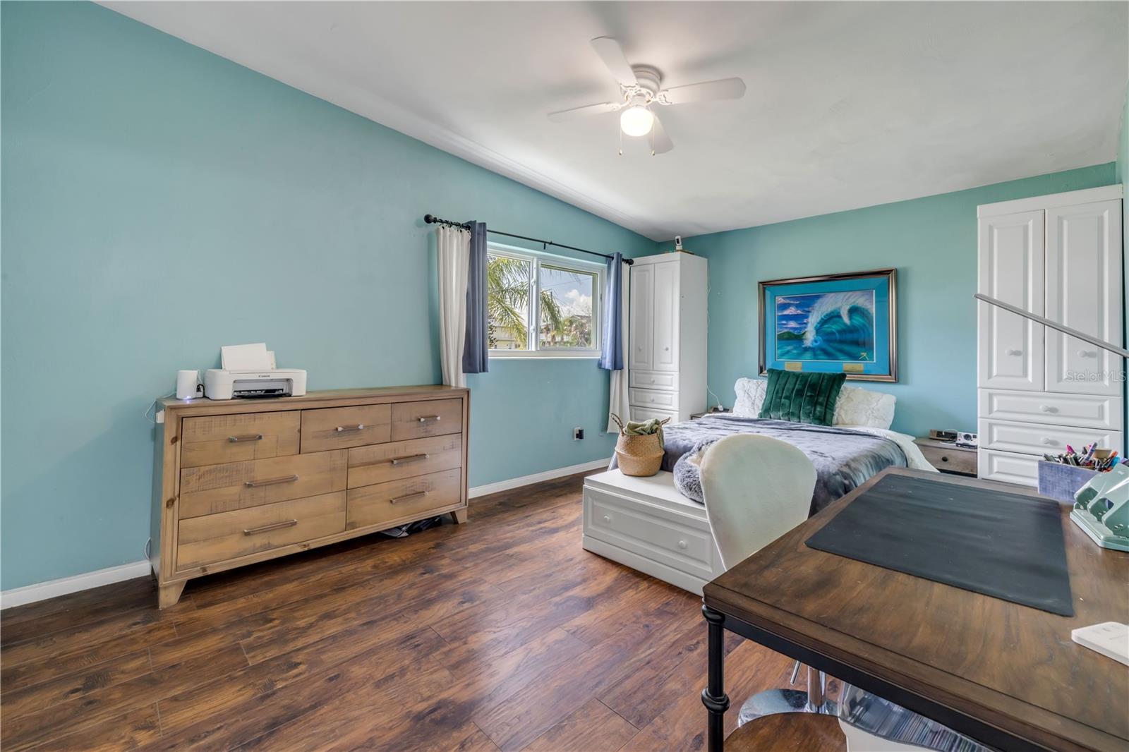 Bedroom with windows, ceiling fan and coastal-blue walls.