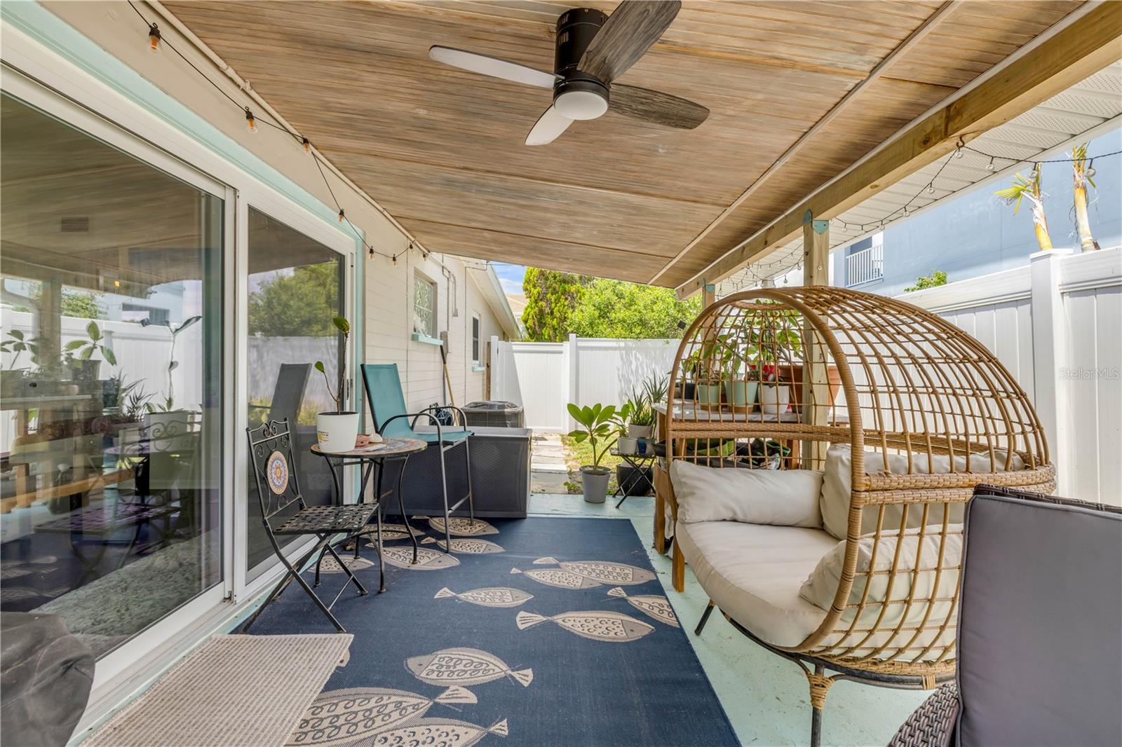 Covered patio with outdoor seating and a hanging chair.