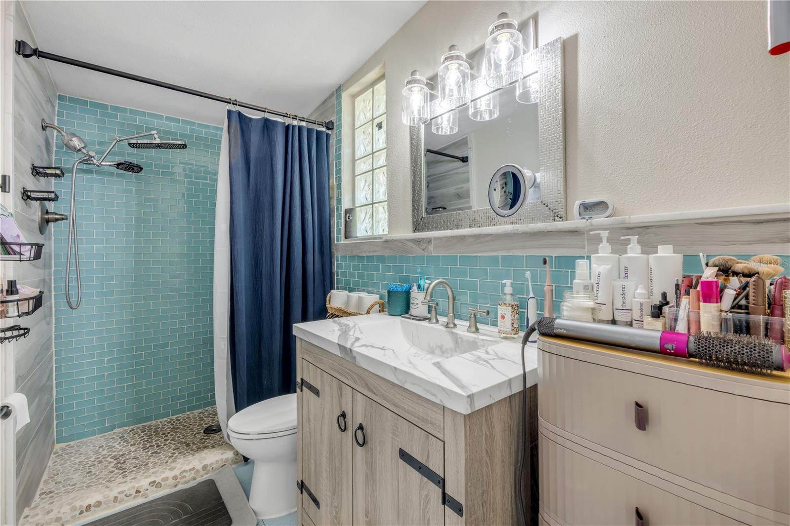 Bathroom with double-sink vanity and a glass-enclosed shower.