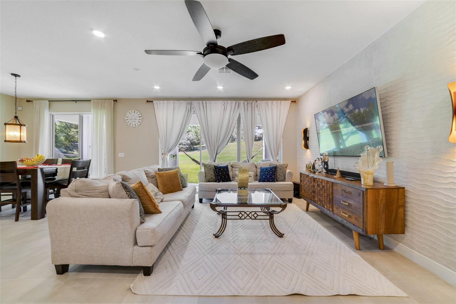 In the living room, enjoy a CUSTOM ACCENT WALL (2023) and views of the large backyard through dual sliding glass doors. In the living room, enjoy a CUSTOM ACCENT WALL (2023) and views of the large backyard through dual sliding glass doors.
