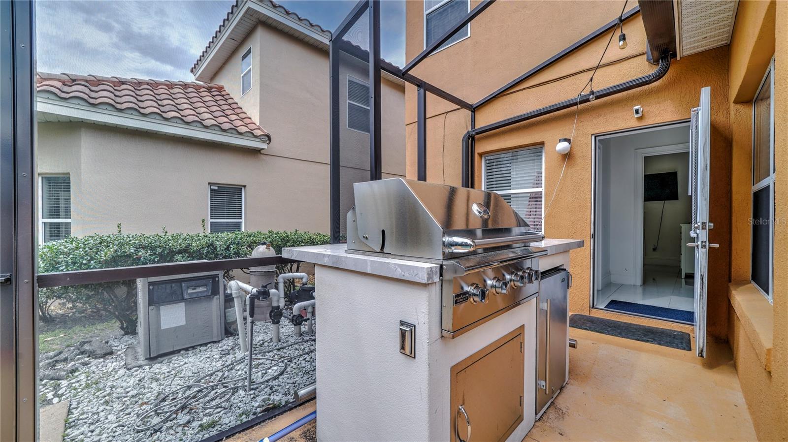 Screened lanai featuring a built-in stainless steel grill.