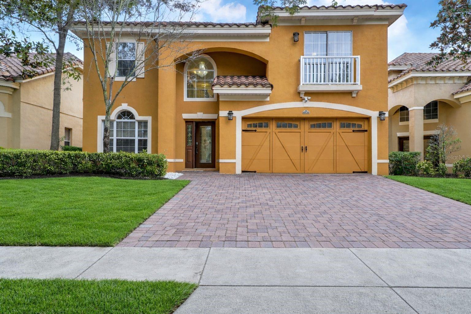 A brick paver driveway leading to a spacious two-car garage with decorative carriage-style doors and black hardware accents. A brick paver driveway leading to a spacious two-car garage with decorative carriage-style doors and black hardware accents.