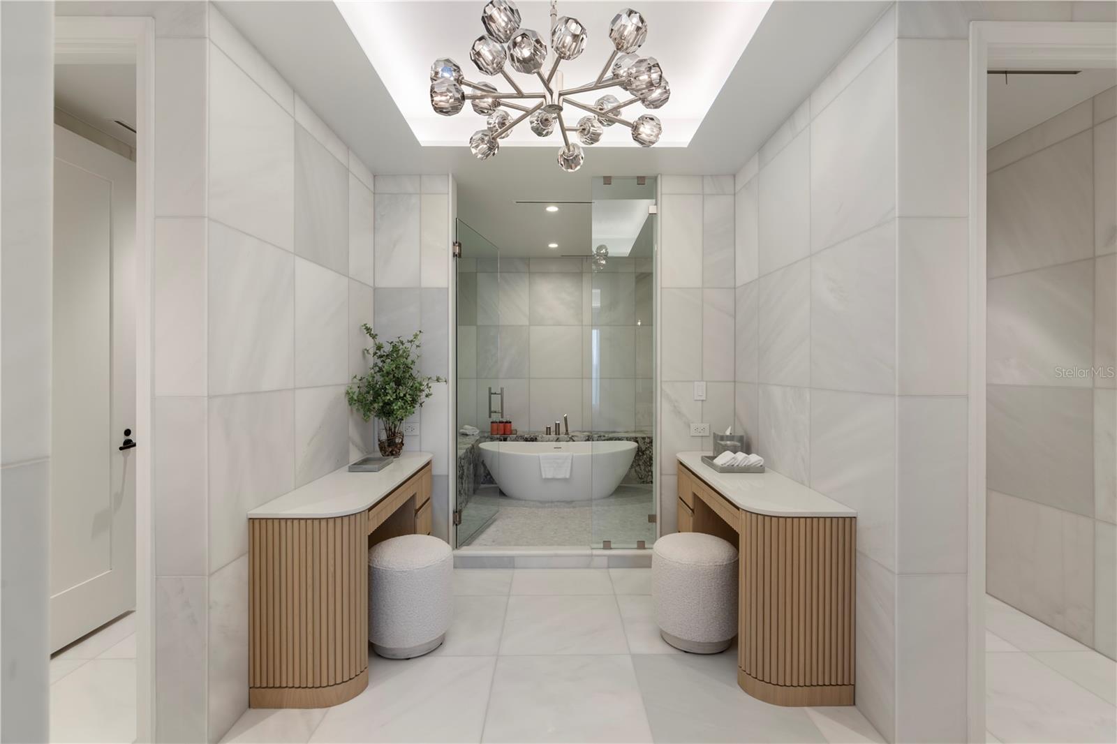 Primary bath with marble floors and walls, wet-room style shower, wet and dry vanities, separate toilet rooms