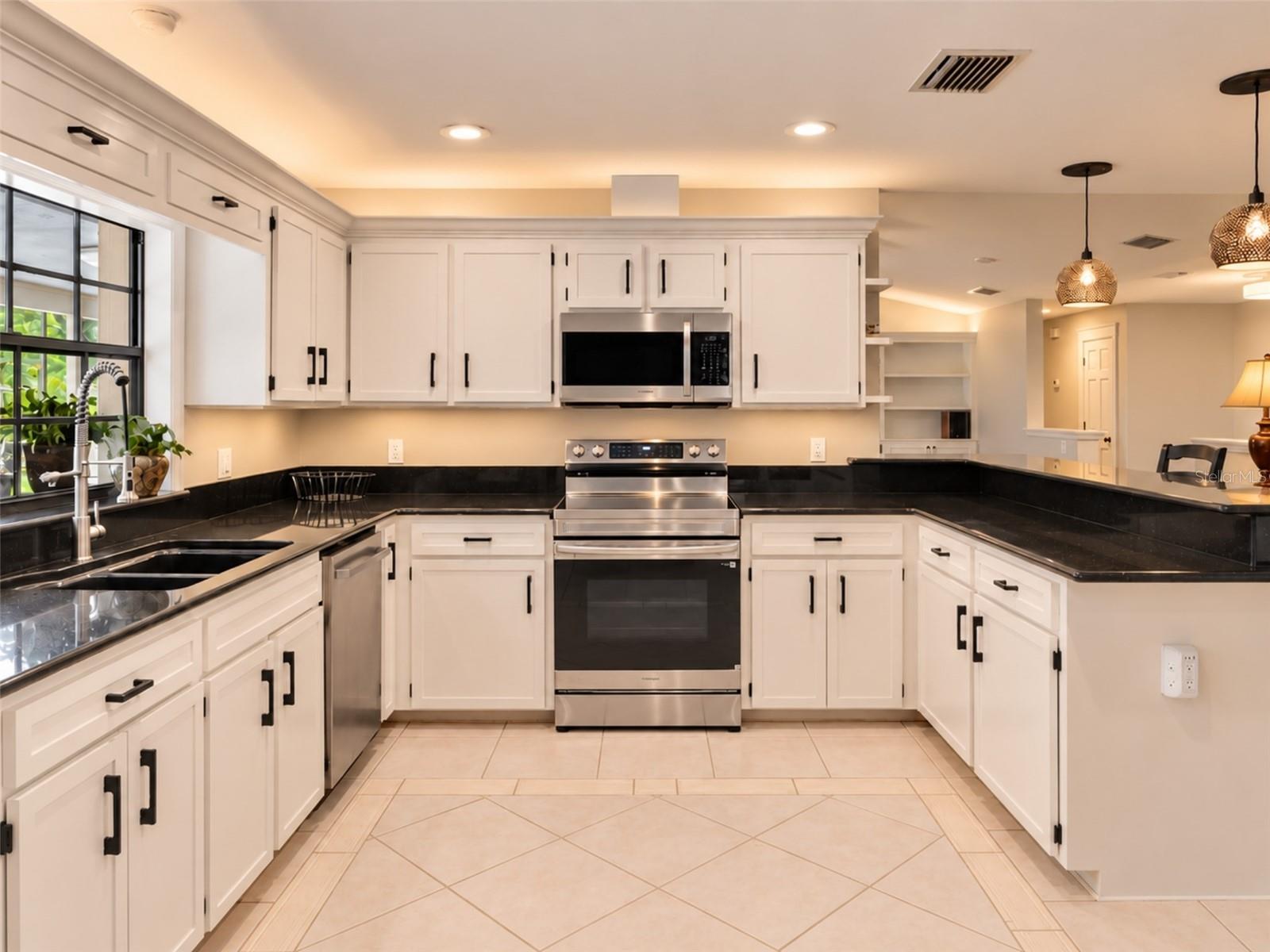 Bright kitchen with abundant cabinetry, granite countertops, stainless steel appliances, and a brand new rang with air fry feature- plus under-and above- cabinet lighting. Pass-through window to the pool with serving counter makes outdoor entertaining effortless.