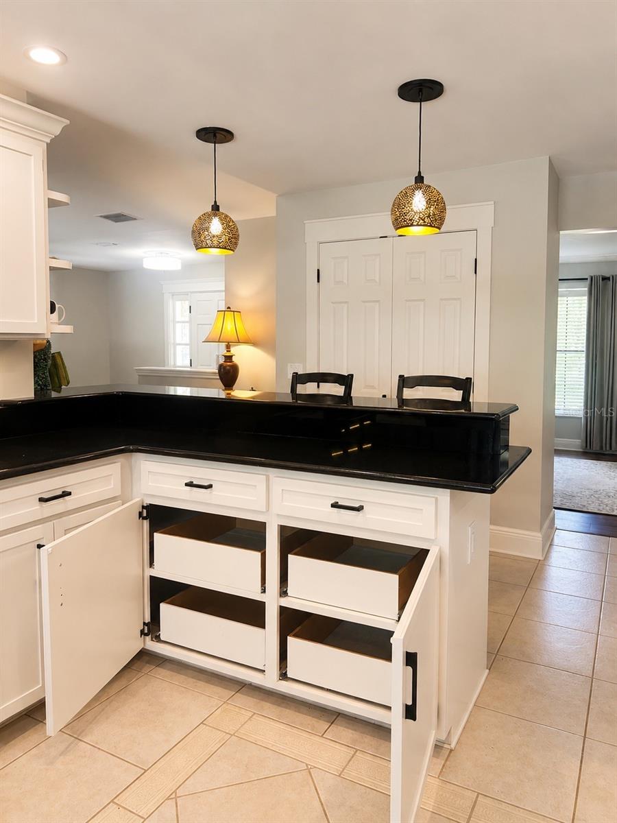 Chic kitchen details shine with warm pendant lighting, a convenient breakfast bar, and pull-out lower cabinets that make storage both stylish and functional.