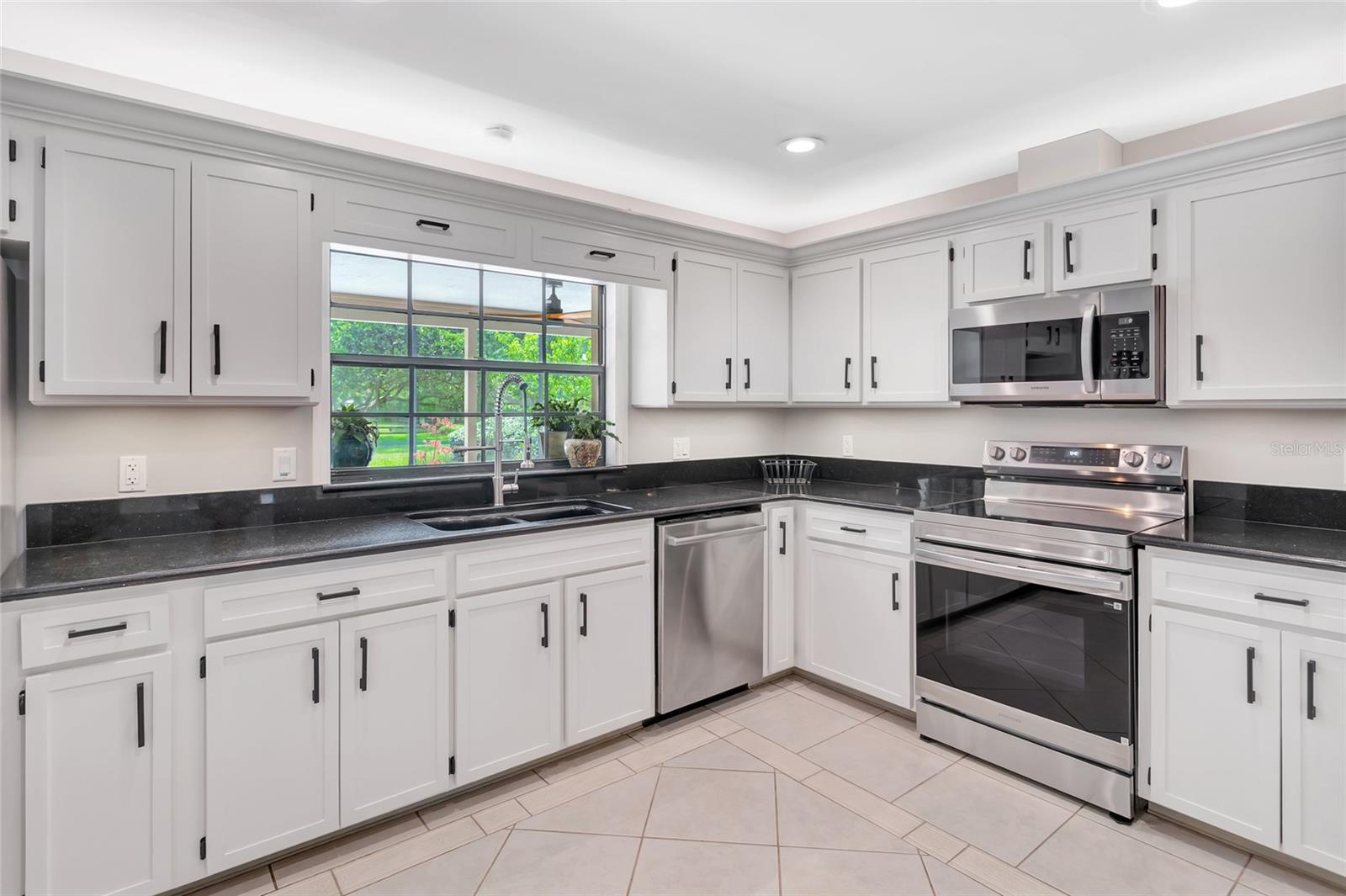 Bright kitchen with abundant cabinetry, granite countertops, stainless steel appliances, and a brand new rang with air fry feature- plus under-and above- cabinet lighting. Pass-through window to the pool with serving counter makes outdoor entertaining effortless.