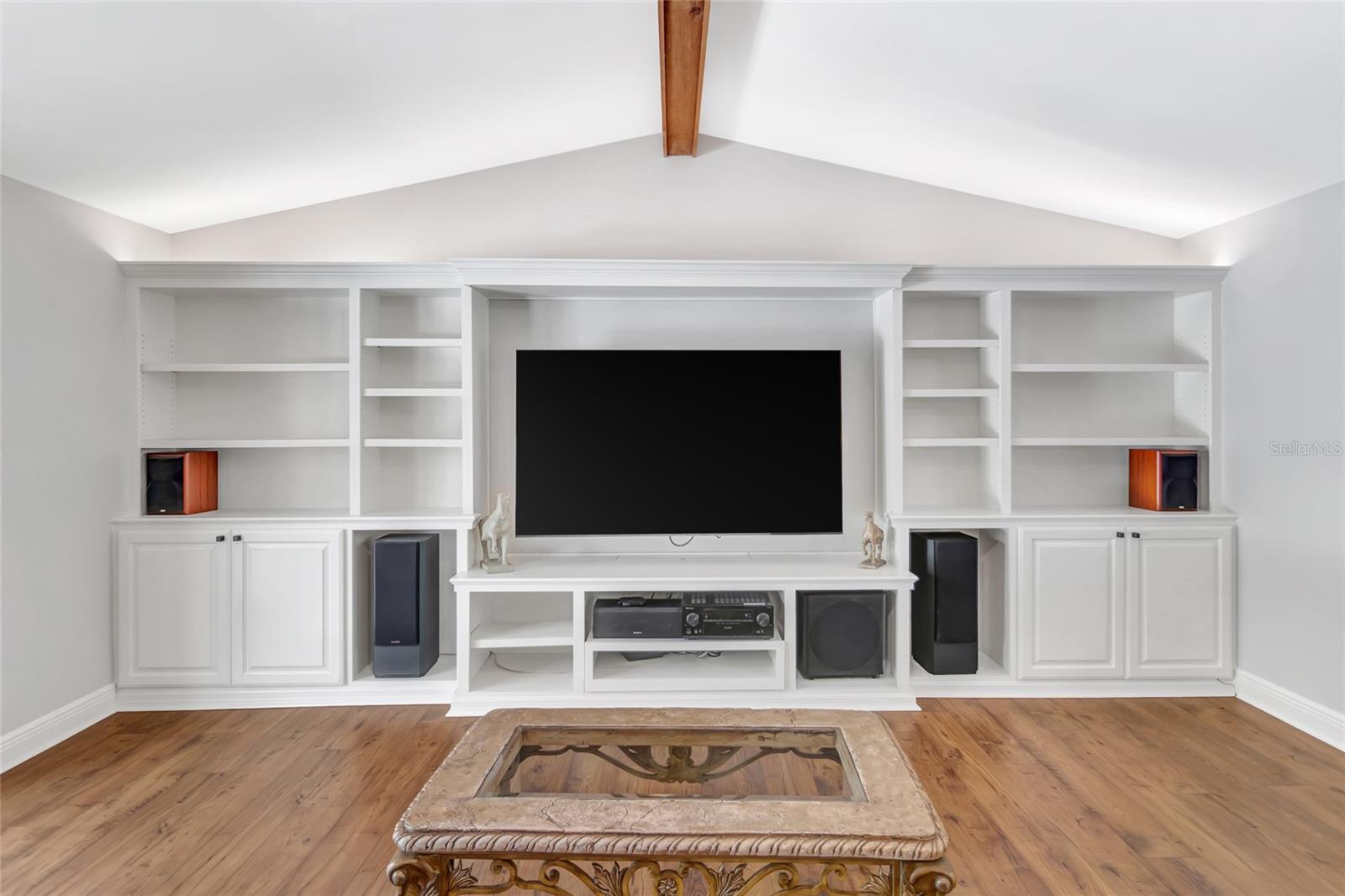 Custom built-in entertainment wall with extensive shelving, cabinetry, and a seamless media setup- designed for both style and function.