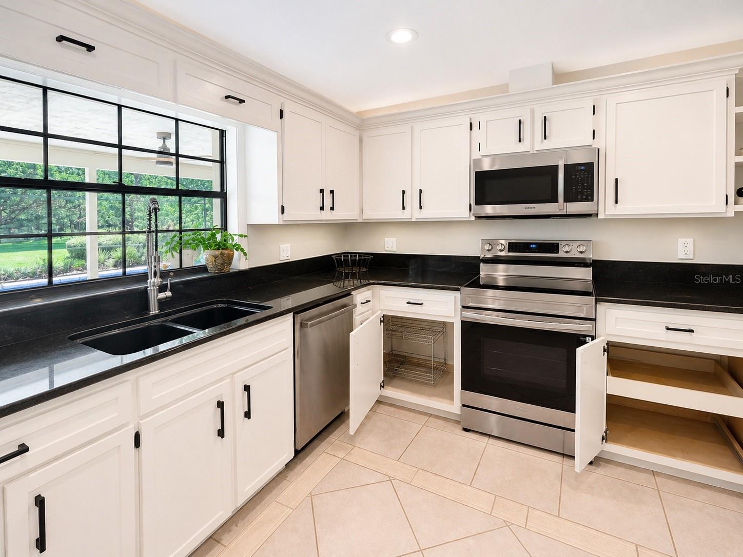 Bright, stylish kitchen with crisp cabinetry, sleep black counters, custom pull outs, and a brand new stove. The pass through window opens right to the pool and patio, making entertaining effortless.