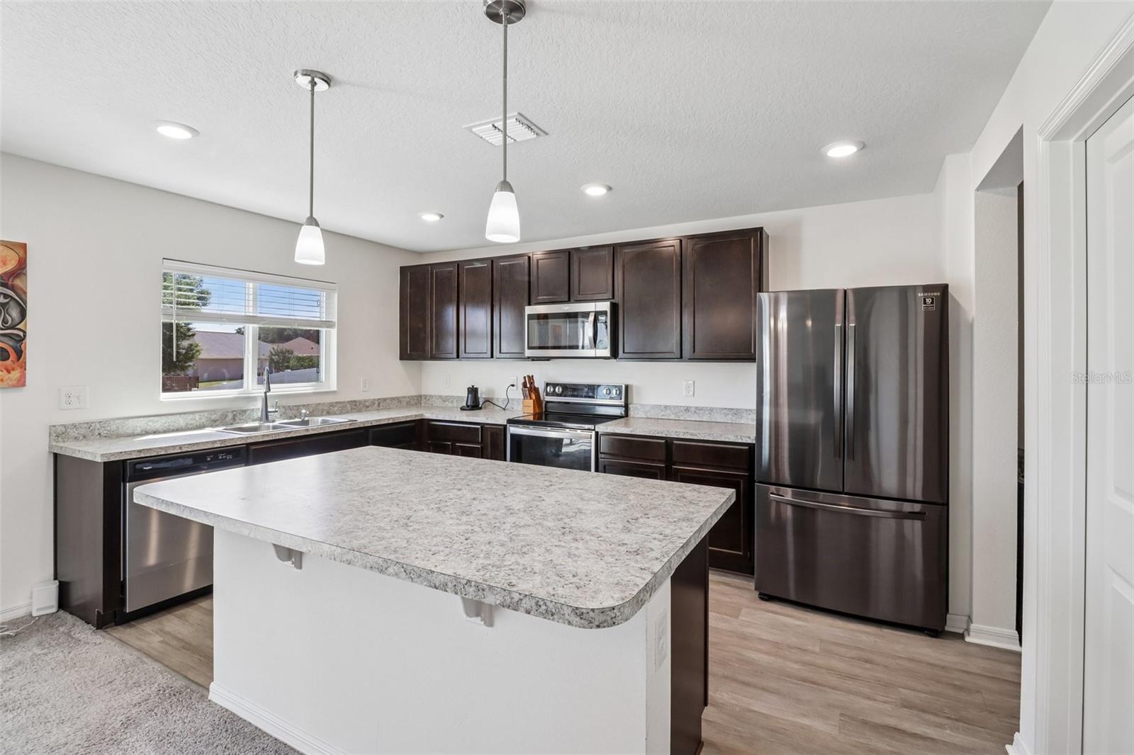 The kitchen offers a comfortable, functional design with rich cabinetry, STAINLESS STEEL APPLIANCES, plenty of counter space, and a large ISLAND with bar seating and pendant lighting. The kitchen offers a comfortable, functional design with rich cabinetry, STAINLESS STEEL APPLIANCES, plenty of counter space, and a large ISLAND with bar seating and pendant lighting.