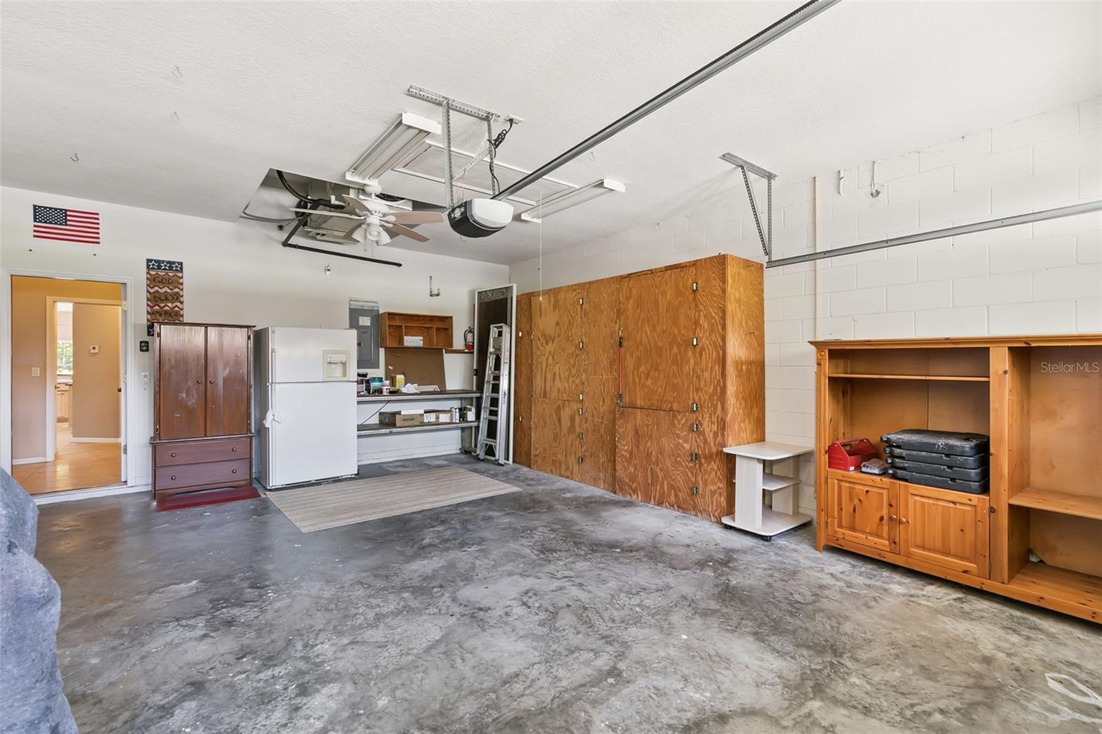Oversized garage with built-in shelves and pull-down ladder system for attic access and additional storage.